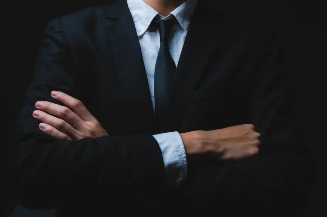 עורך דין עם חליפה יוקרתית משלב ידיים, המחשה לעורך דין שמטפל בתהליך תביעה לפינוי מושכר.